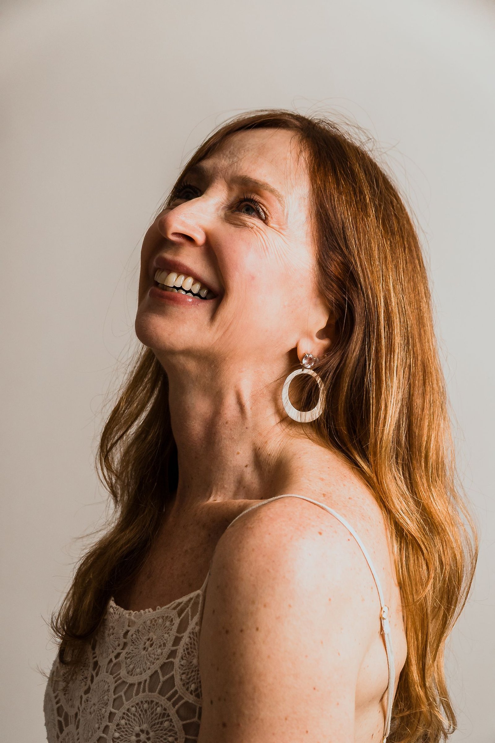 Charming portrait of a mature woman with a warm smile and elegant earrings, exuding confidence.